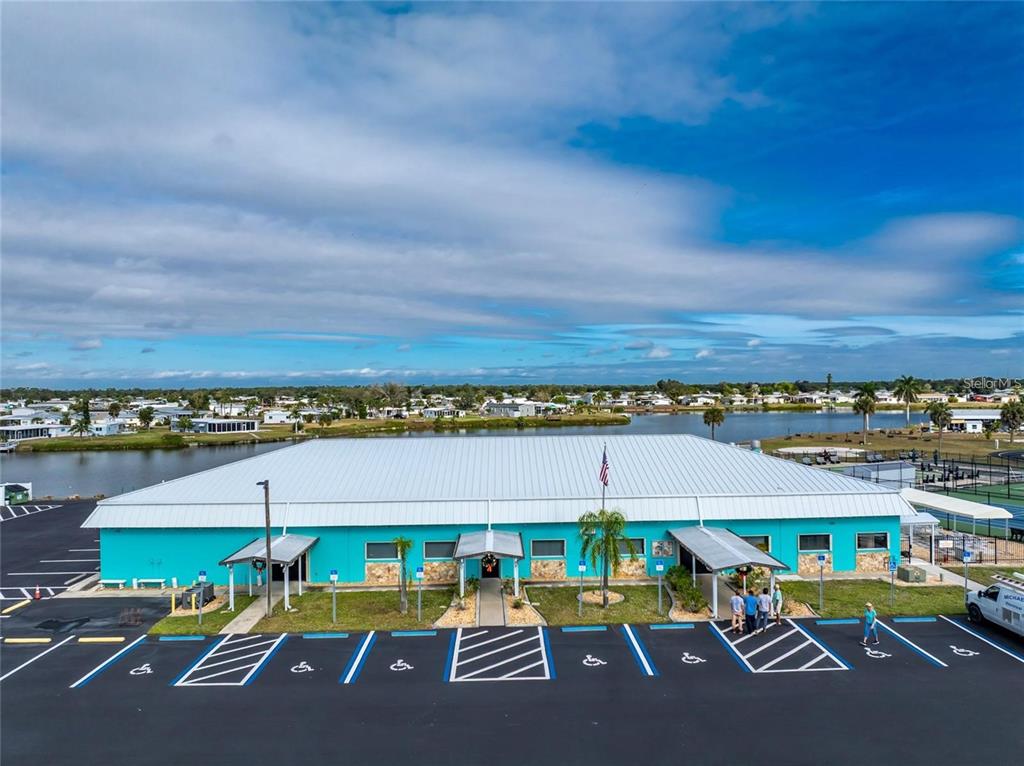 An exterior view of a teal community building with a metal roof and parking lot — 1538 BLUE HERON DRIVE, ENGLEWOOD, FL