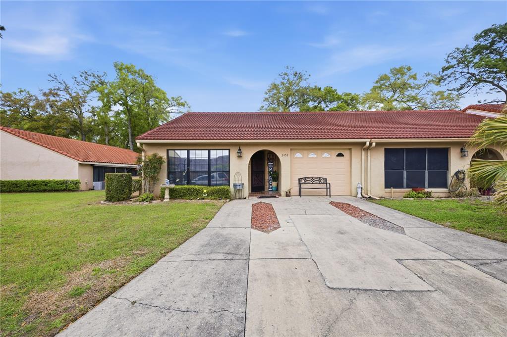 A single-story house with a red tile roof, beige stucco exterior, and a concrete driveway — 3455 SW 19TH STREET, OCALA, FL