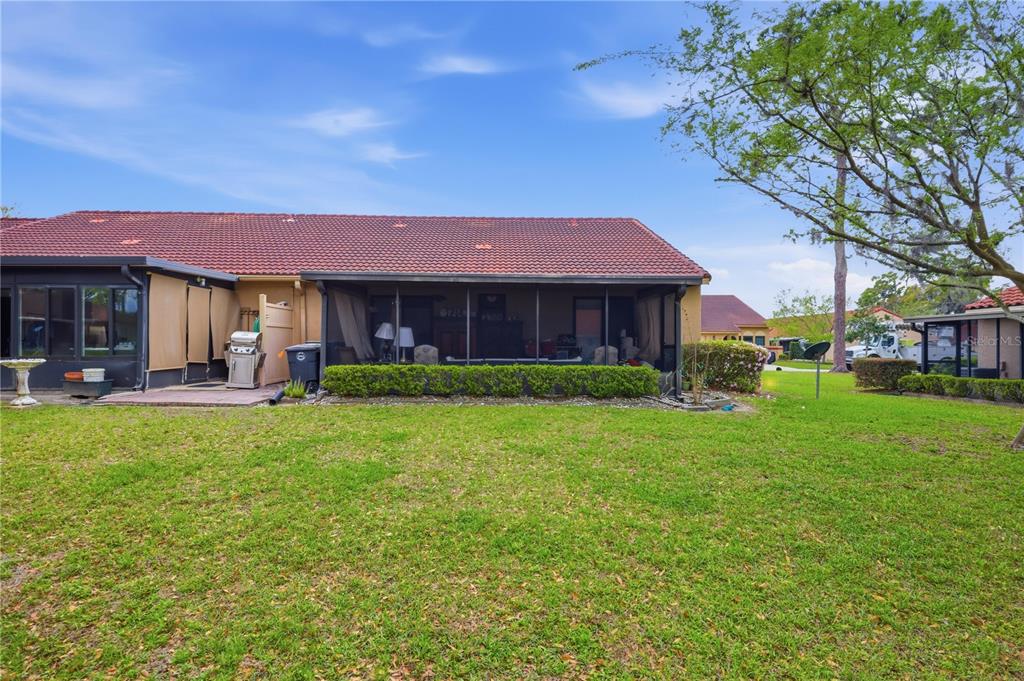 The exterior of a house features a screened-in patio, a tiled roof, and a lawn — 3455 SW 19TH STREET, OCALA, FL