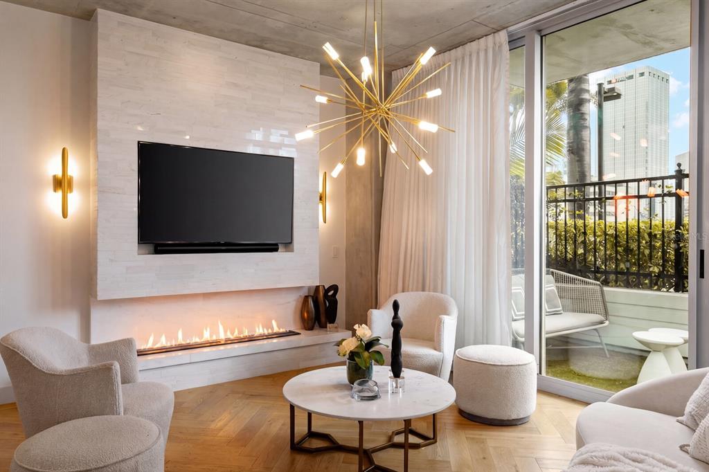 A modern living room features a linear fireplace, a sputnik chandelier, and a balcony view — 777 N ASHLEY DRIVE UNIT 806, TAMPA, FL