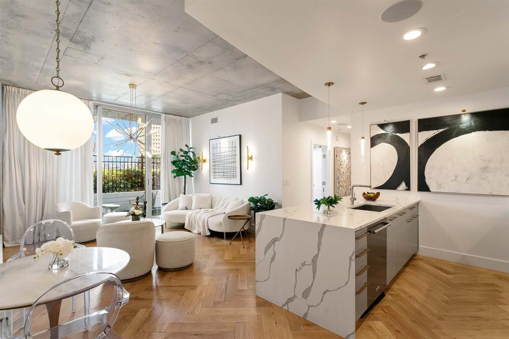 A modern open-concept living area features a kitchen island, herringbone wood floors, and concrete ceilings — 777 N ASHLEY DRIVE UNIT 806, TAMPA, FL