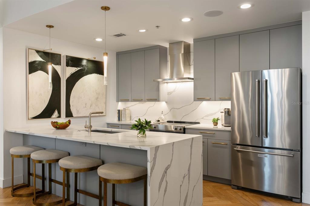 A modern kitchen features gray cabinetry, a marble waterfall island, and stainless steel appliances — 777 N ASHLEY DRIVE UNIT 806, TAMPA, FL