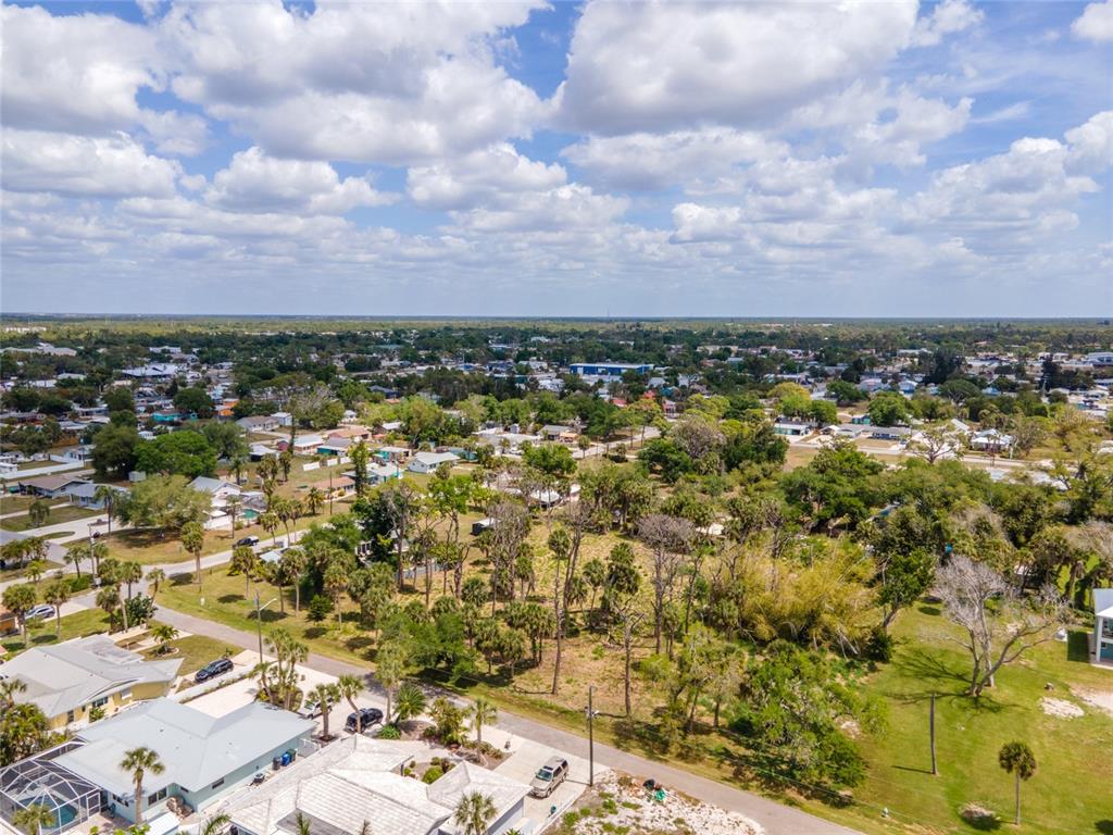 An aerial view shows a residential neighborhood with houses, palm trees, and a vacant lot — W COWLES STREET, ENGLEWOOD, FL