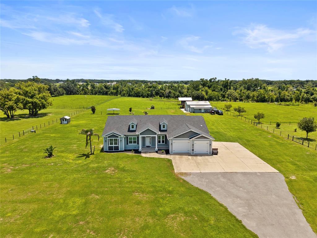 An aerial view shows a single-story house with a two-car garage on a large lot — 15710 COLDING LOOP, WIMAUMA, FL