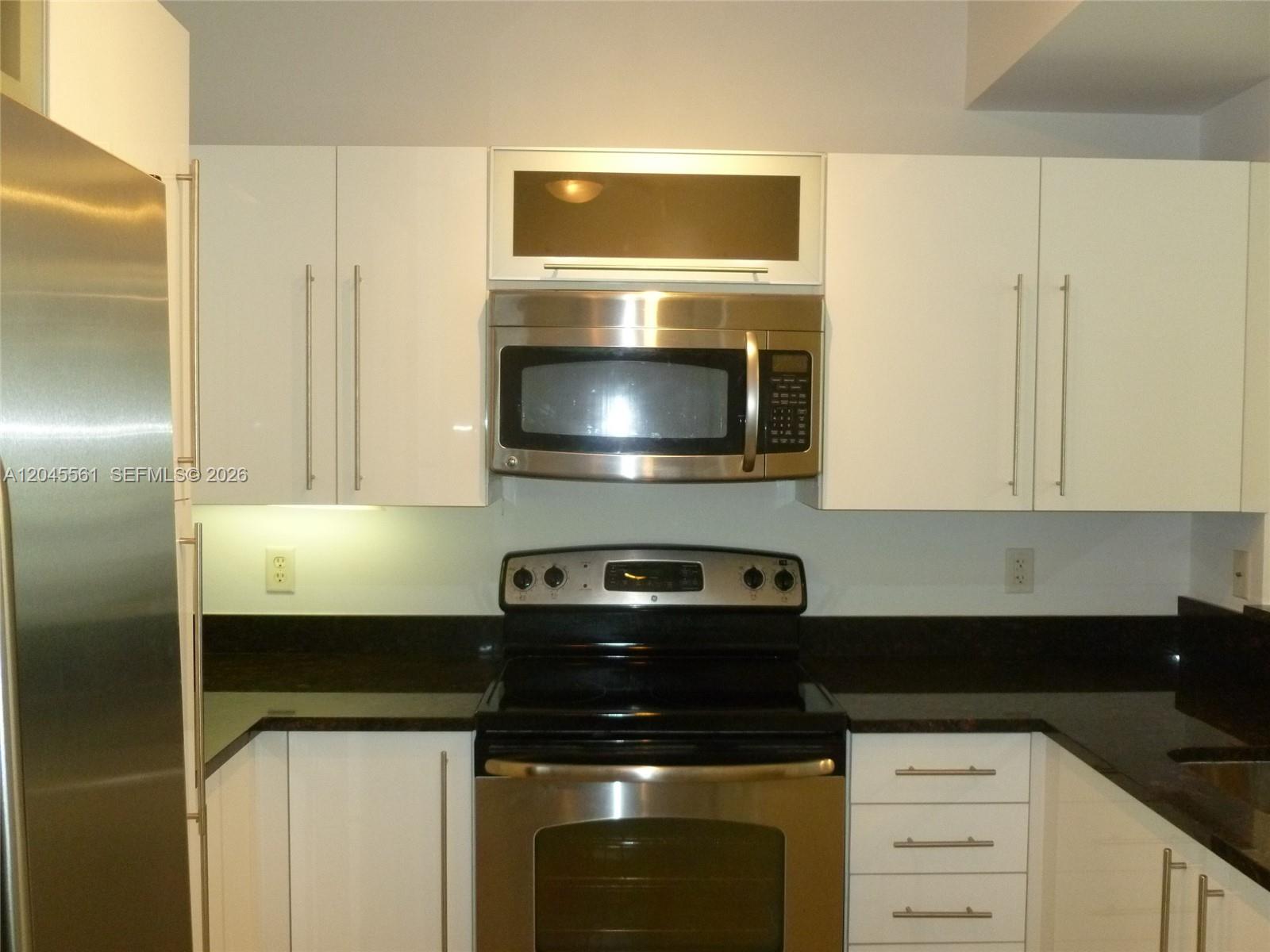A kitchen features white cabinets, stainless steel appliances, and dark countertops — 7350 SW 89th St # 807S, Miami FL 33156, MIAMI, FL