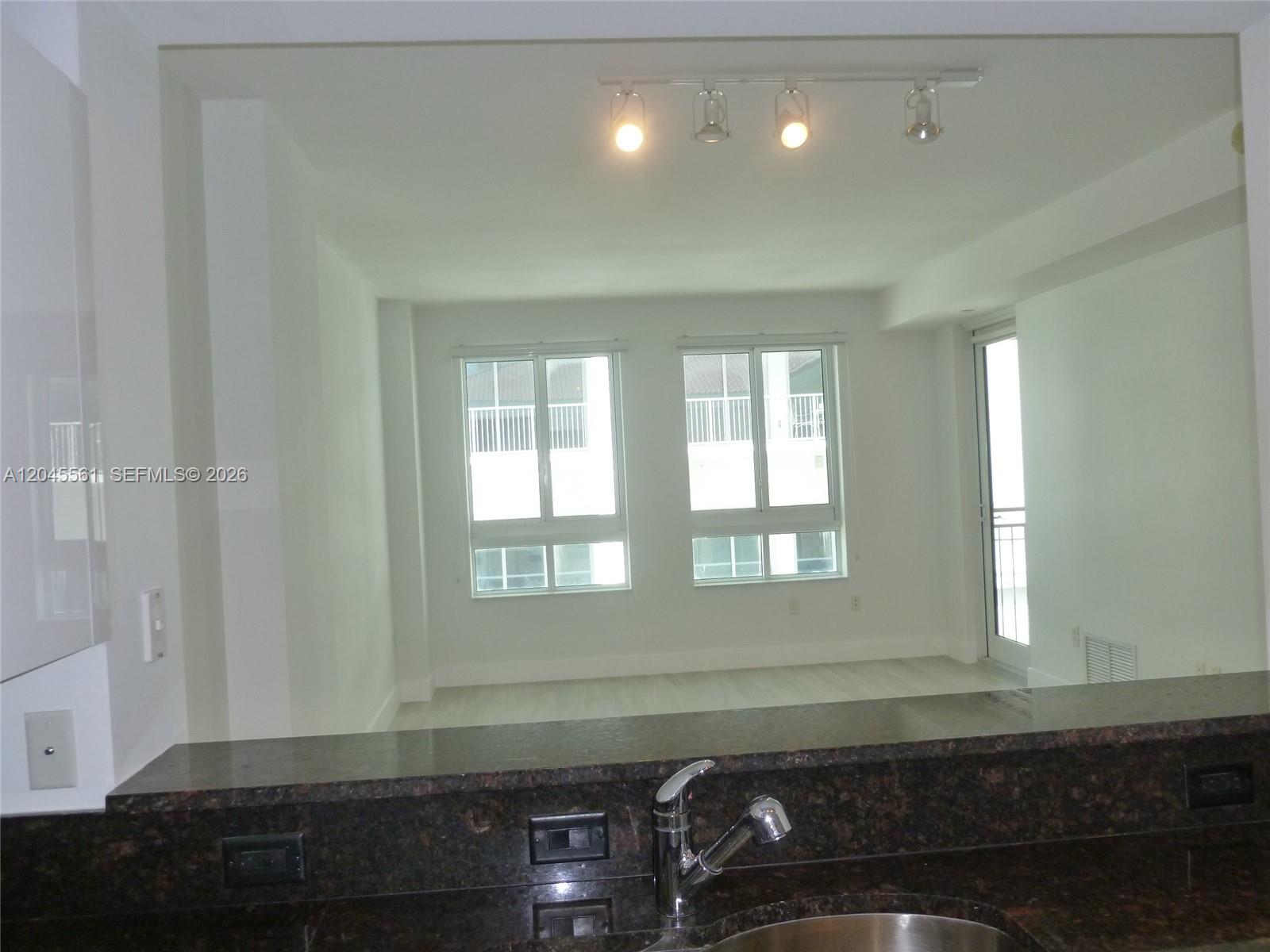 A kitchen counter with a dark granite top overlooks a bright, empty living area — 7350 SW 89th St # 807S, Miami FL 33156, MIAMI, FL
