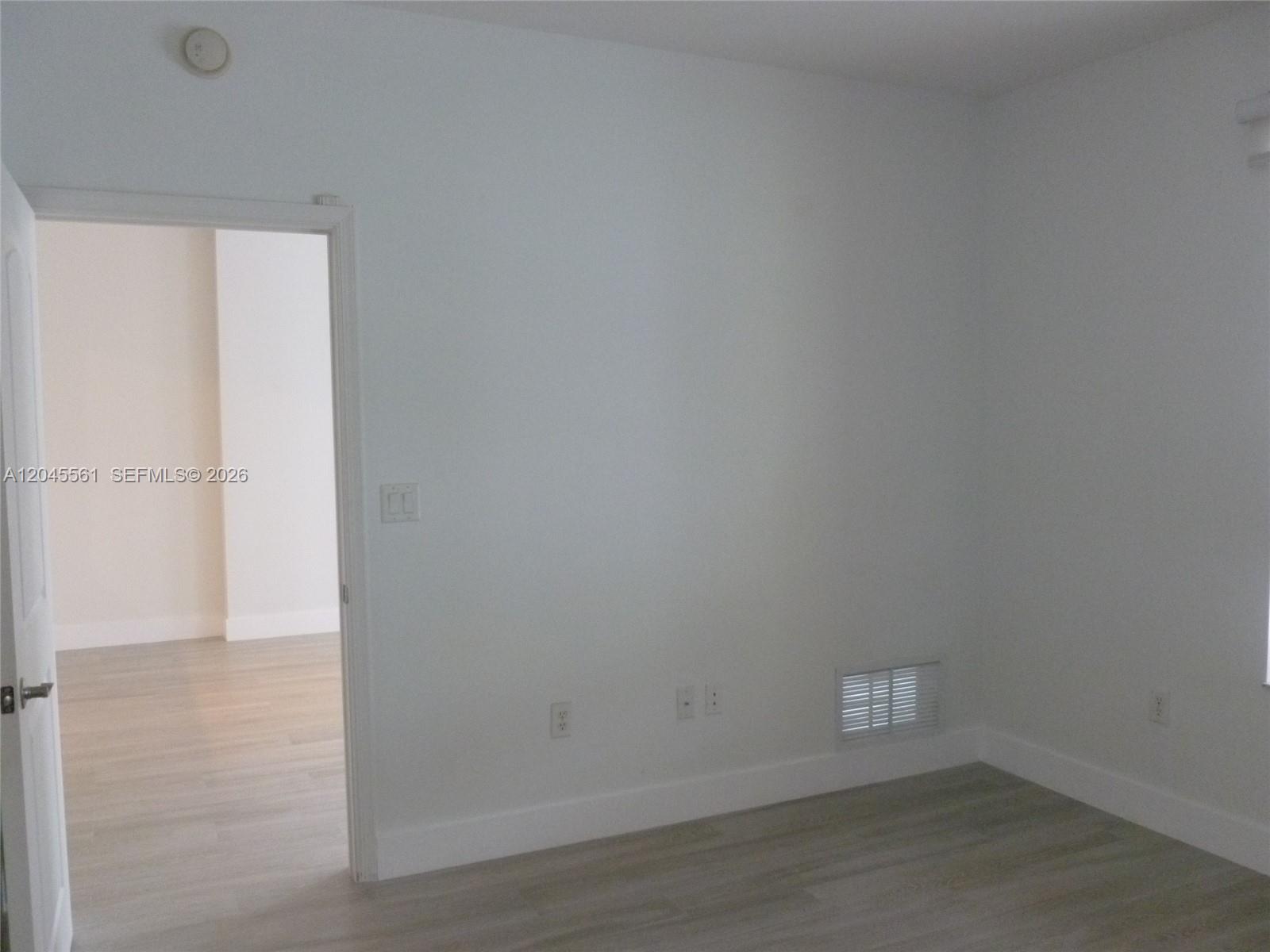 An empty room features light-colored wood-look flooring, white walls, and a doorway leading elsewhere — 7350 SW 89th St # 807S, Miami FL 33156, MIAMI, FL