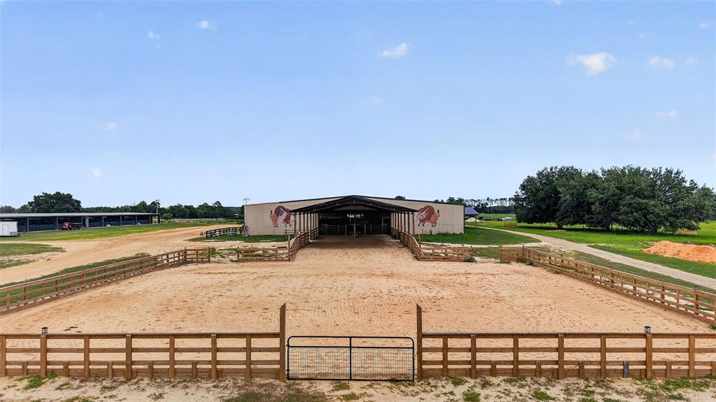 An outdoor horse riding arena features a fenced perimeter and a large covered barn structure — 40812 GRAYS AIRPORT ROAD, LADY LAKE, FL