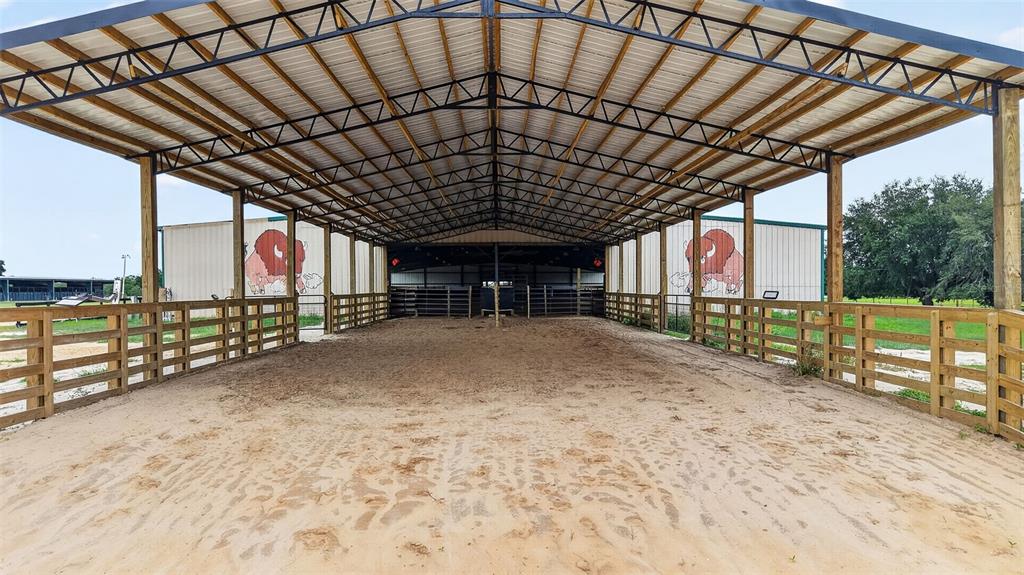An open-air equestrian riding arena features a sand floor, wooden fencing, and metal roofing — 40812 GRAYS AIRPORT ROAD, LADY LAKE, FL