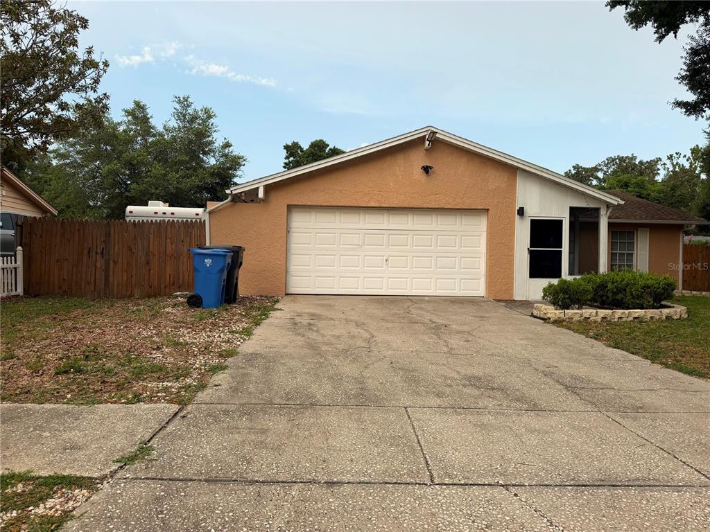 A single-story house with a tan stucco exterior, a two-car garage, and a concrete driveway — 2206 PAVILION PLACE, BRANDON, FL