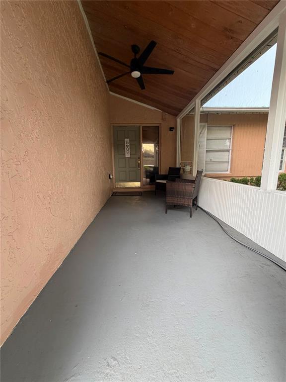 A covered patio features a gray floor, wood-paneled ceiling, ceiling fan, and wicker chairs — 2206 PAVILION PLACE, BRANDON, FL