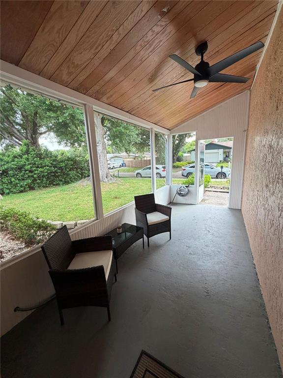 A screened-in porch with a wood-paneled ceiling, ceiling fan, and two wicker chairs — 2206 PAVILION PLACE, BRANDON, FL
