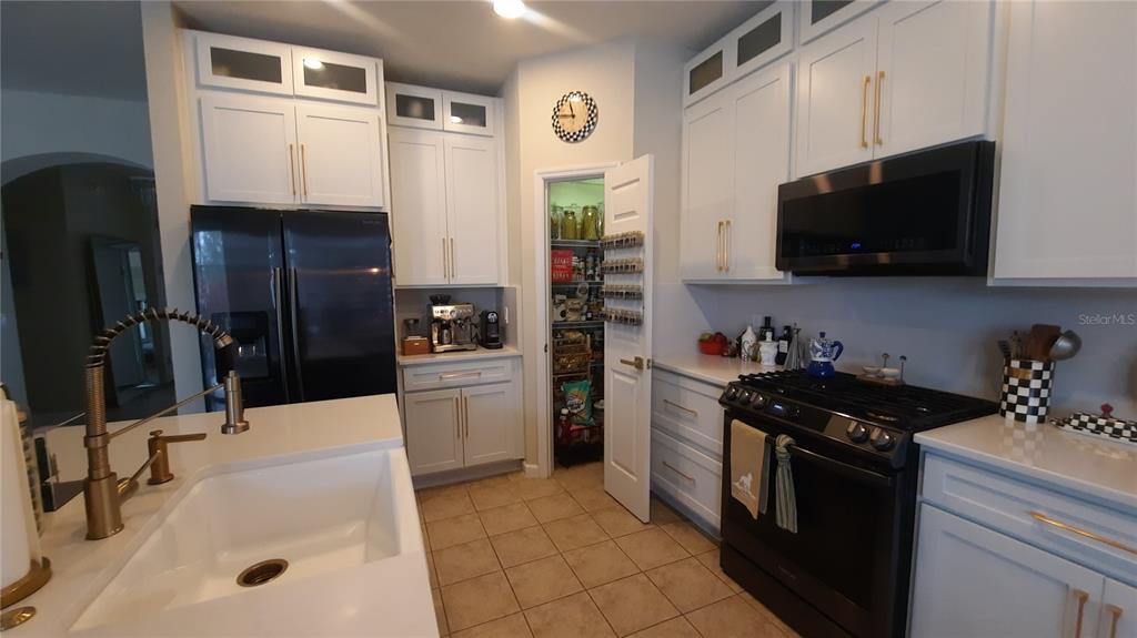 A kitchen features white cabinetry, a black refrigerator, a gas range, and a walk-in pantry — 4959 THAMES STREET E, KISSIMMEE, FL