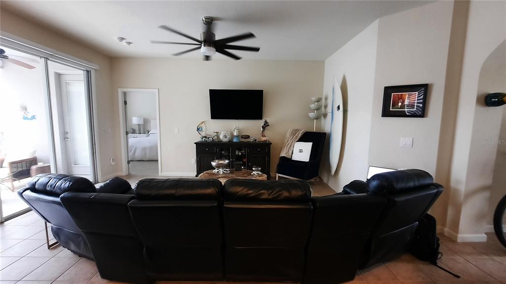 A living room features a black leather sectional sofa, a television, and a surfboard — 4959 THAMES STREET E, KISSIMMEE, FL