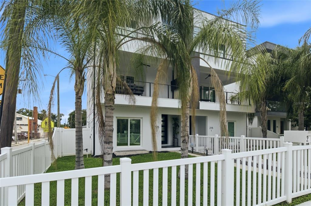 A modern white multi-story townhouse features a second-floor balcony and a white picket fence — 215 W COLUMBUS DRIVE UNIT 2, TAMPA, FL