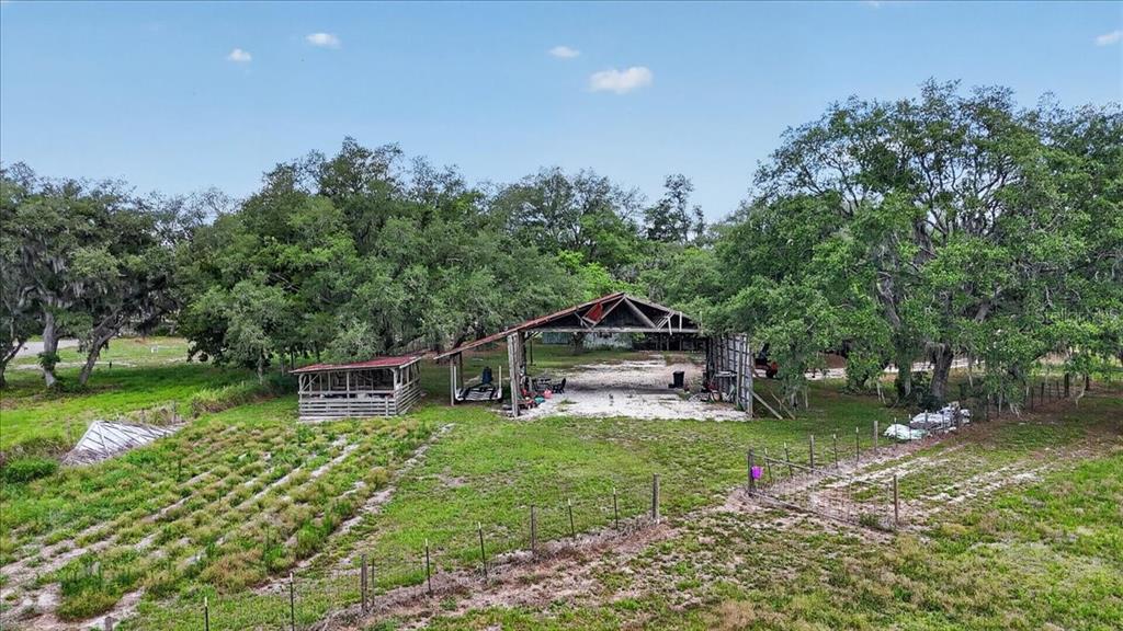 An aerial view shows a rural property with a large open-sided barn and garden plots — 7505 274TH STREET E, MYAKKA CITY, FL