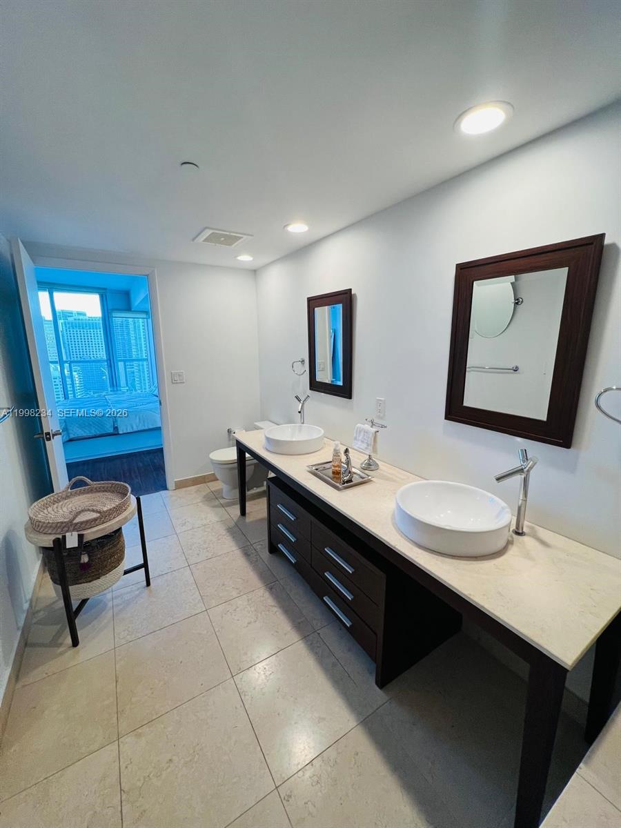 A bathroom features a double vanity with vessel sinks, dark cabinets, and light tile flooring — 495 Brickell ave # 2707, Miami FL 33131, MIAMI, FL