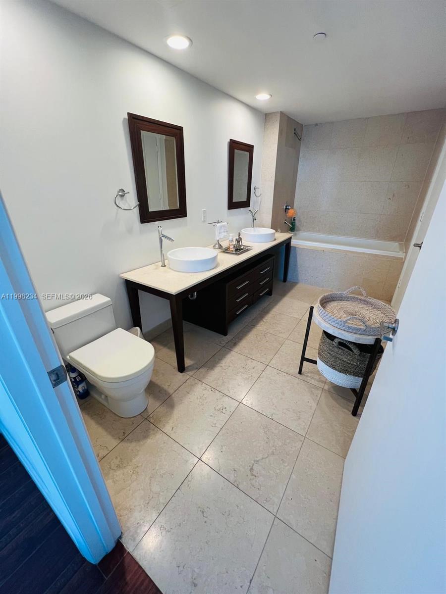 A bathroom features a double vanity with vessel sinks, a toilet, and a tiled bathtub — 495 Brickell ave # 2707, Miami FL 33131, MIAMI, FL