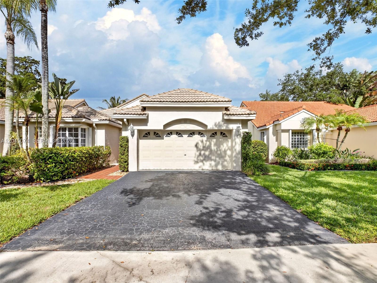 A single-story house with a beige stucco exterior, a two-car garage, and a paved driveway — 1520 Seabay Rd, Weston FL 33326, WESTON, FL