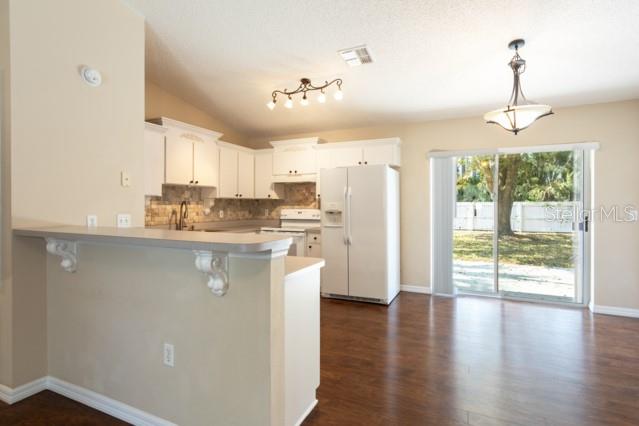 A kitchen with white cabinets, a breakfast bar, and a sliding glass door to outside — 3 PINE HAVEN DRIVE, PALM COAST, FL