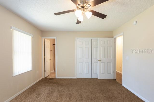 A bedroom with beige walls, brown carpeting, a ceiling fan, and white closet doors — 3 PINE HAVEN DRIVE, PALM COAST, FL