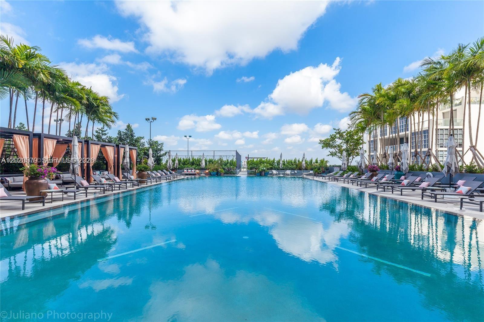 A large outdoor swimming pool is surrounded by lounge chairs, cabanas, and palm trees — 121 NE 34th St # 1007, Miami FL 33137, MIAMI, FL