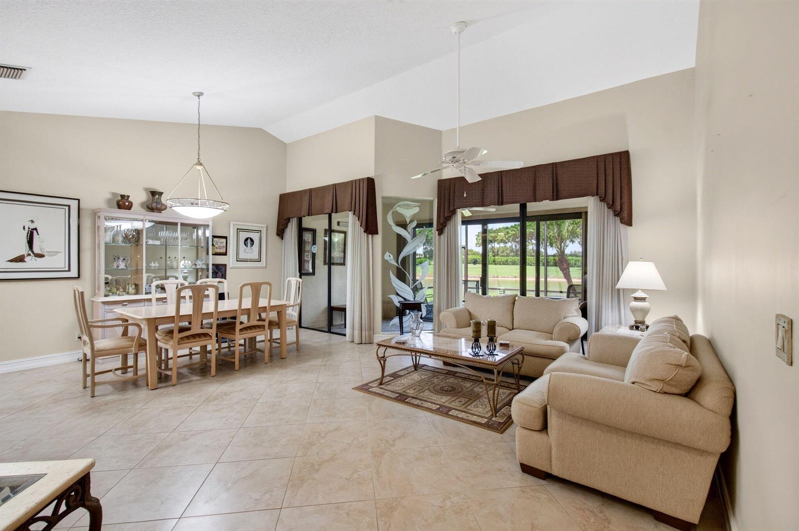 A living and dining room with tile floors, beige furniture, and sliding glass doors to outdoors — 7481 Hearth Stone Avenue, Boynton Beach FL 33472, BOYNTON BEACH, FL