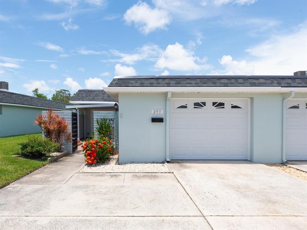 A light blue single-story house features a white garage door and a small front courtyard — 295 BOCA CIEGA POINT BOULEVARD N, ST PETERSBURG, FL