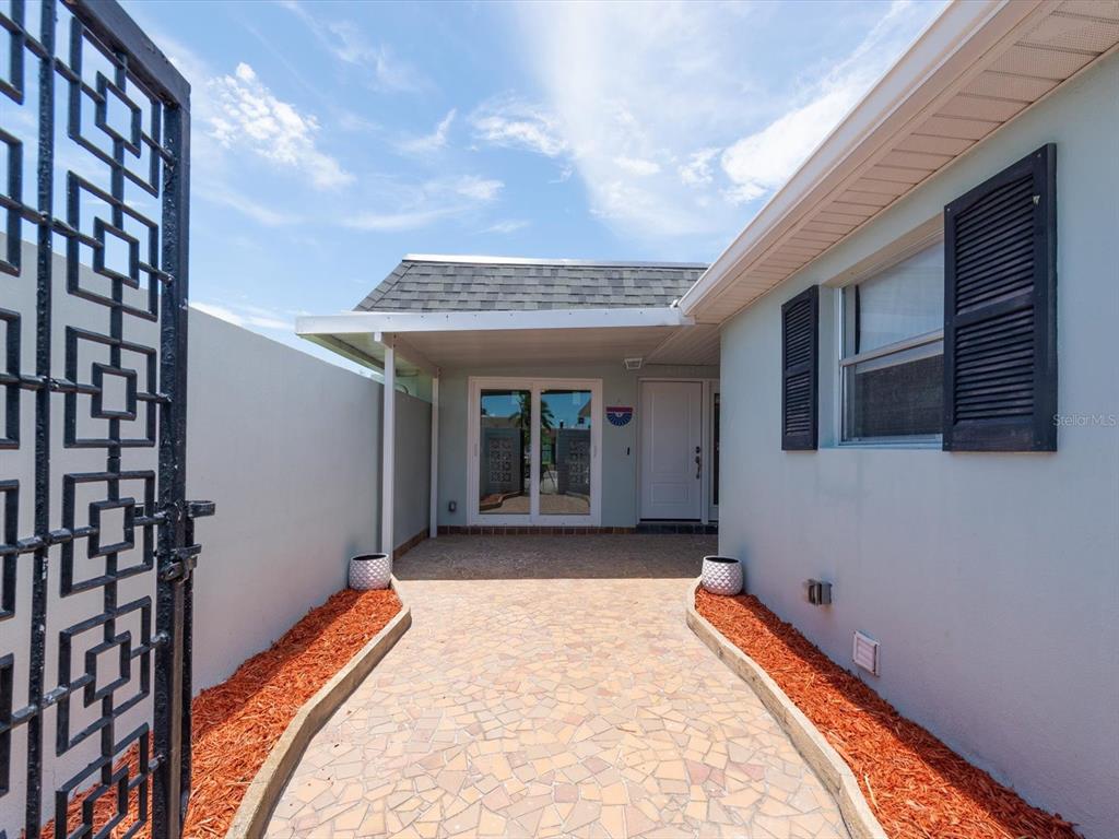 A paved walkway leads to a covered entryway with a white door and glass doors — 295 BOCA CIEGA POINT BOULEVARD N, ST PETERSBURG, FL