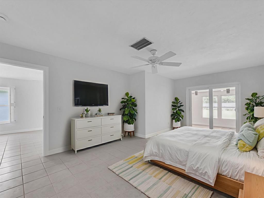 A bedroom with light tile flooring, a white dresser, a bed, and sliding glass doors — 295 BOCA CIEGA POINT BOULEVARD N, ST PETERSBURG, FL