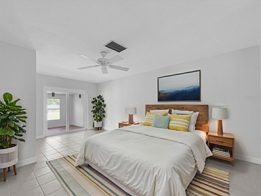 A bedroom features a bed with a wooden headboard, tile flooring, and a sliding glass door — 295 BOCA CIEGA POINT BOULEVARD N, ST PETERSBURG, FL