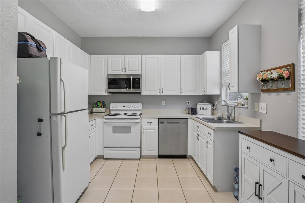 A kitchen with white cabinets, stainless steel appliances, and light-colored tile flooring — 34842 TEEVIEW LANE, ZEPHYRHILLS, FL