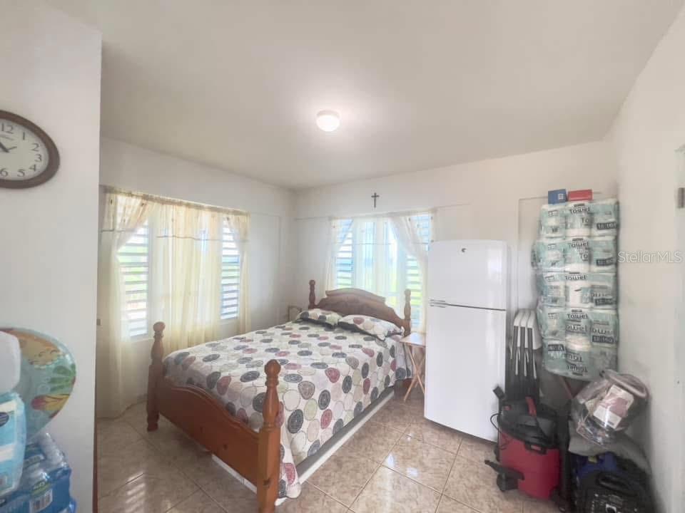 A bedroom features a wooden bed, a white refrigerator, and a stack of paper towels — 901 AMAZING VIEW HOUSE, MAUNABO, PR