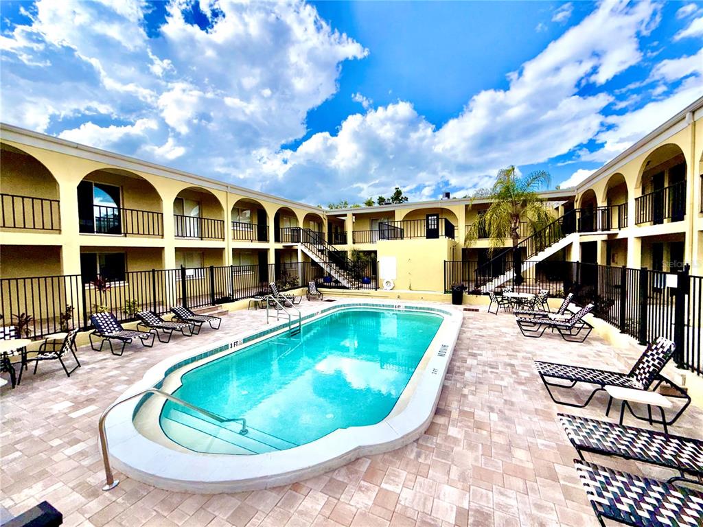An outdoor swimming pool surrounded by a paved deck and a two-story apartment building — 3206 W AZEELE STREET UNIT 100, TAMPA, FL