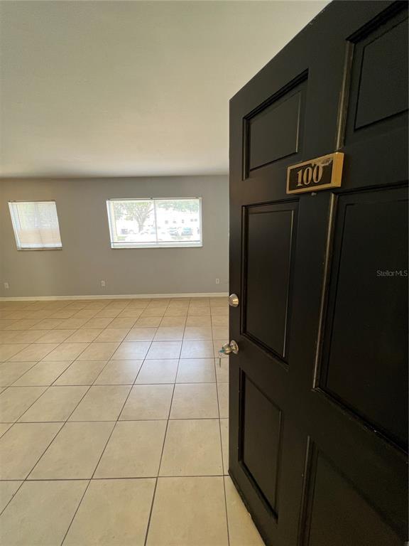 An open black door reveals a room with light-colored tile flooring and two windows — 3206 W AZEELE STREET UNIT 100, TAMPA, FL