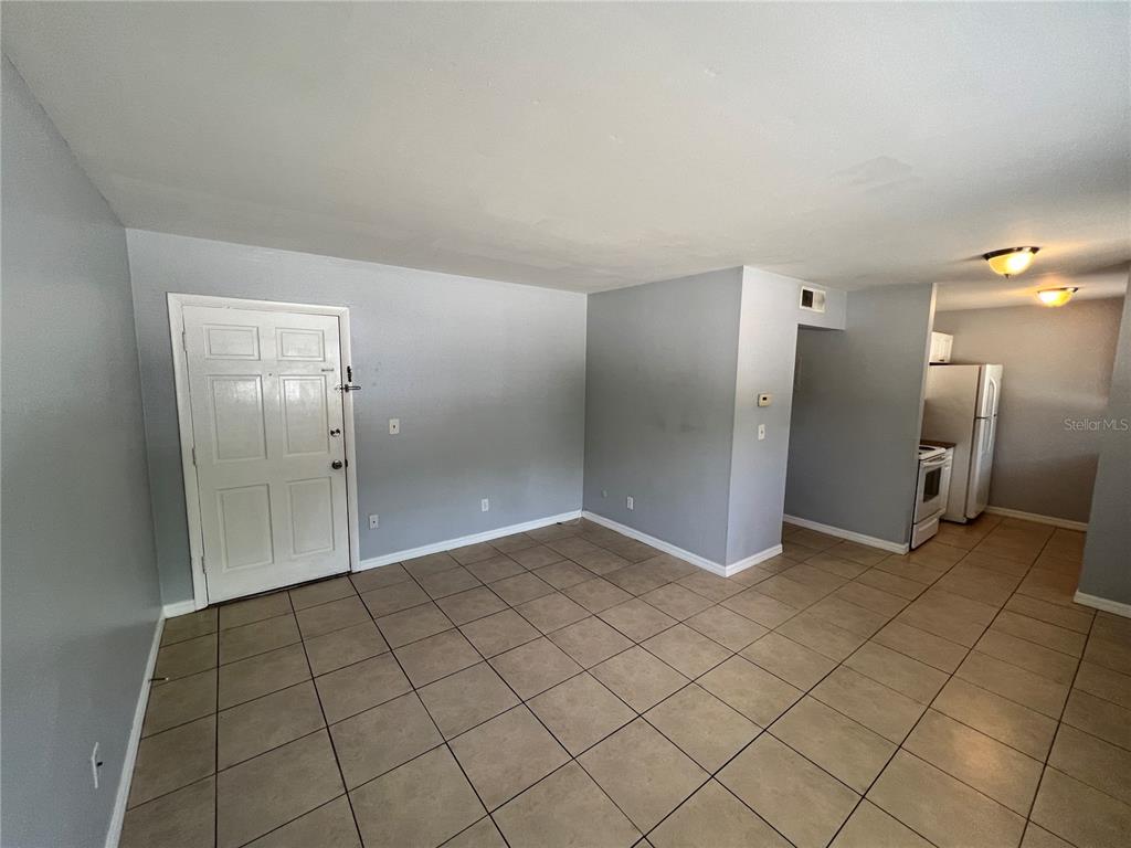 An interior view shows a living area with light gray walls and beige tile flooring — 3206 W AZEELE STREET UNIT 100, TAMPA, FL