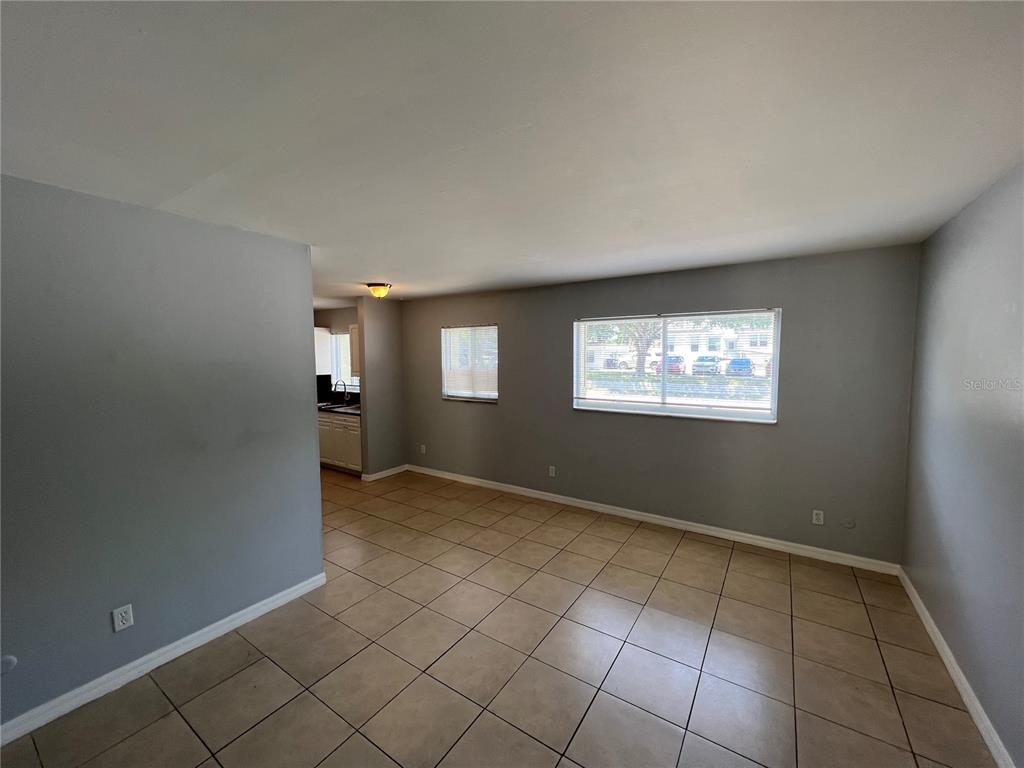 An empty living room with light gray walls, tile flooring, and two windows — 3206 W AZEELE STREET UNIT 100, TAMPA, FL