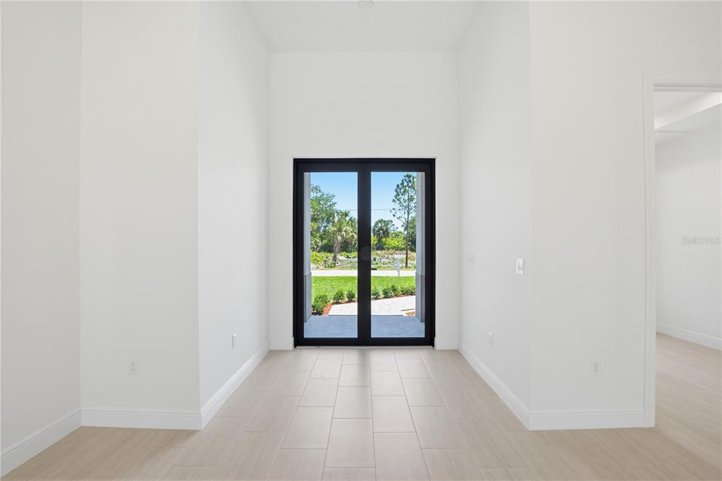 A bright entryway features white walls, light tile flooring, and black-framed double glass doors — 5073 HIGHTOWER ROAD, NORTH PORT, FL