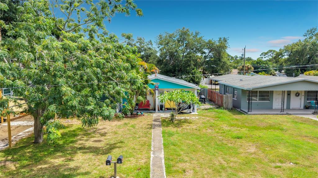 An exterior view shows a turquoise house with a front porch and a grassy yard — 5710 19TH AVENUE S, GULFPORT, FL