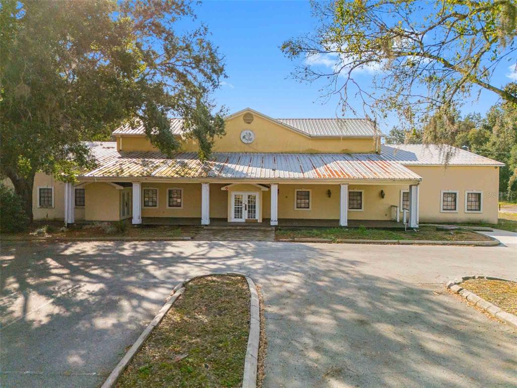 A yellow single-story building with a metal roof and a covered front porch — 10511 MAIN STREET, THONOTOSASSA, FL