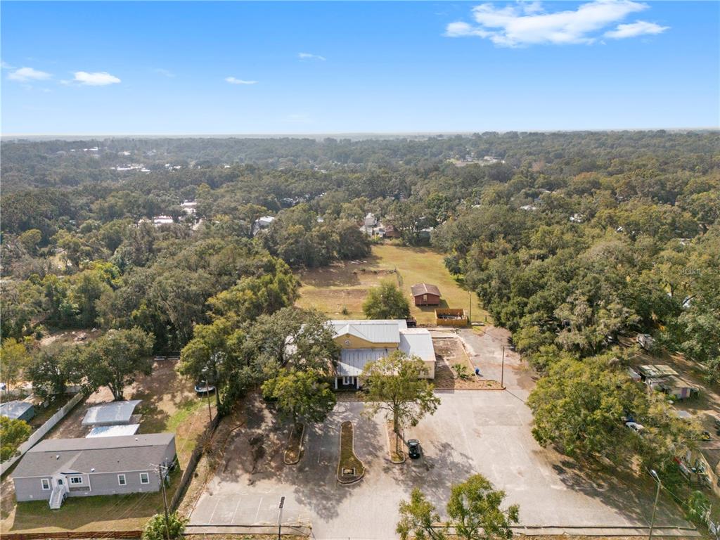 An aerial view shows a commercial building with a parking lot surrounded by trees — 10511 MAIN STREET, THONOTOSASSA, FL
