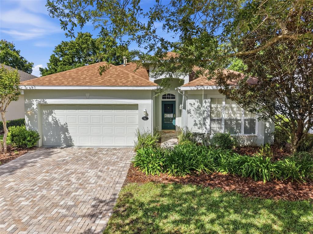 A single-story house with a tan roof, white stucco exterior, and a paved driveway — 115 AVENHAM DRIVE, DELAND, FL