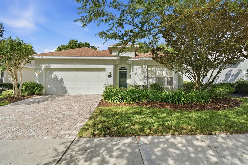 A single-story house with a paved driveway, a two-car garage, and a green front door — 115 AVENHAM DRIVE, DELAND, FL
