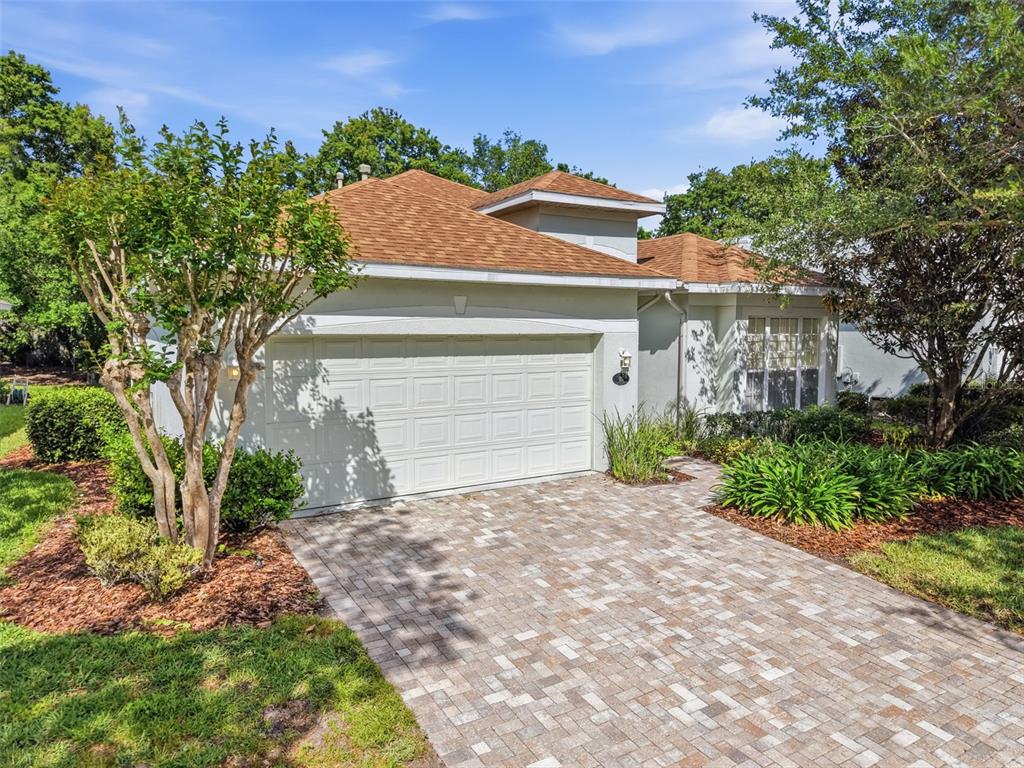 A single-story house with a white garage door and a paved driveway under a blue sky — 115 AVENHAM DRIVE, DELAND, FL
