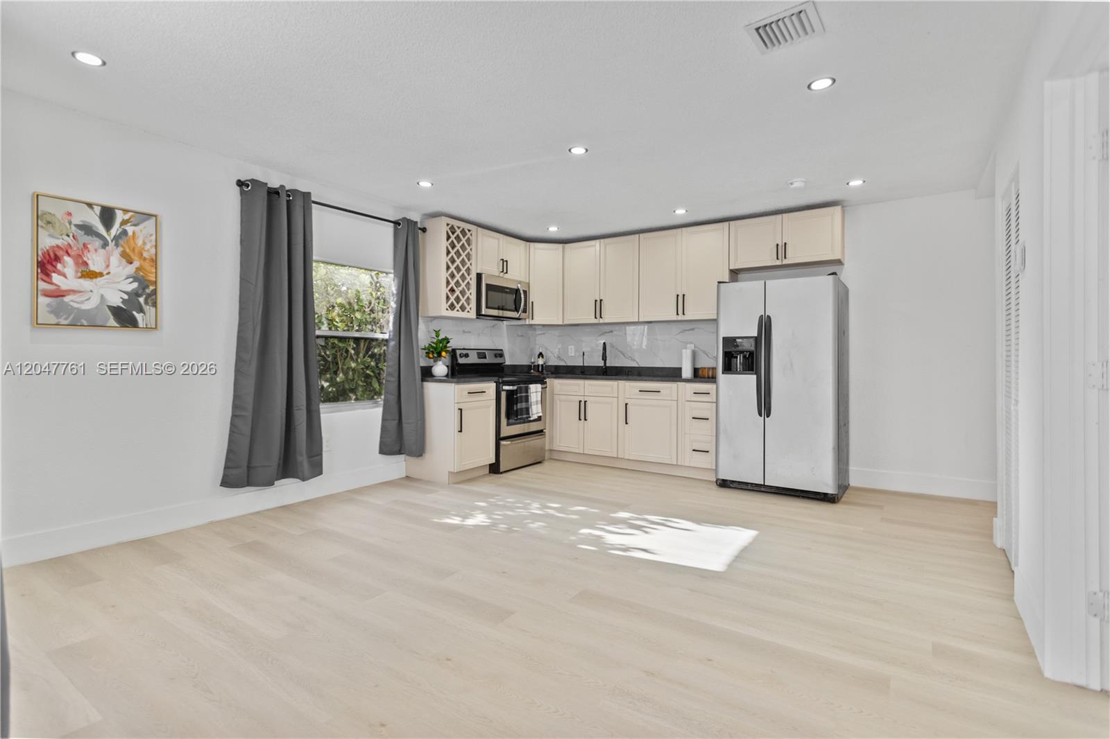 This kitchen features light-colored cabinets, stainless steel appliances, and light wood flooring — 171 W 13th St # 171, Hialeah FL 33010, HIALEAH, FL