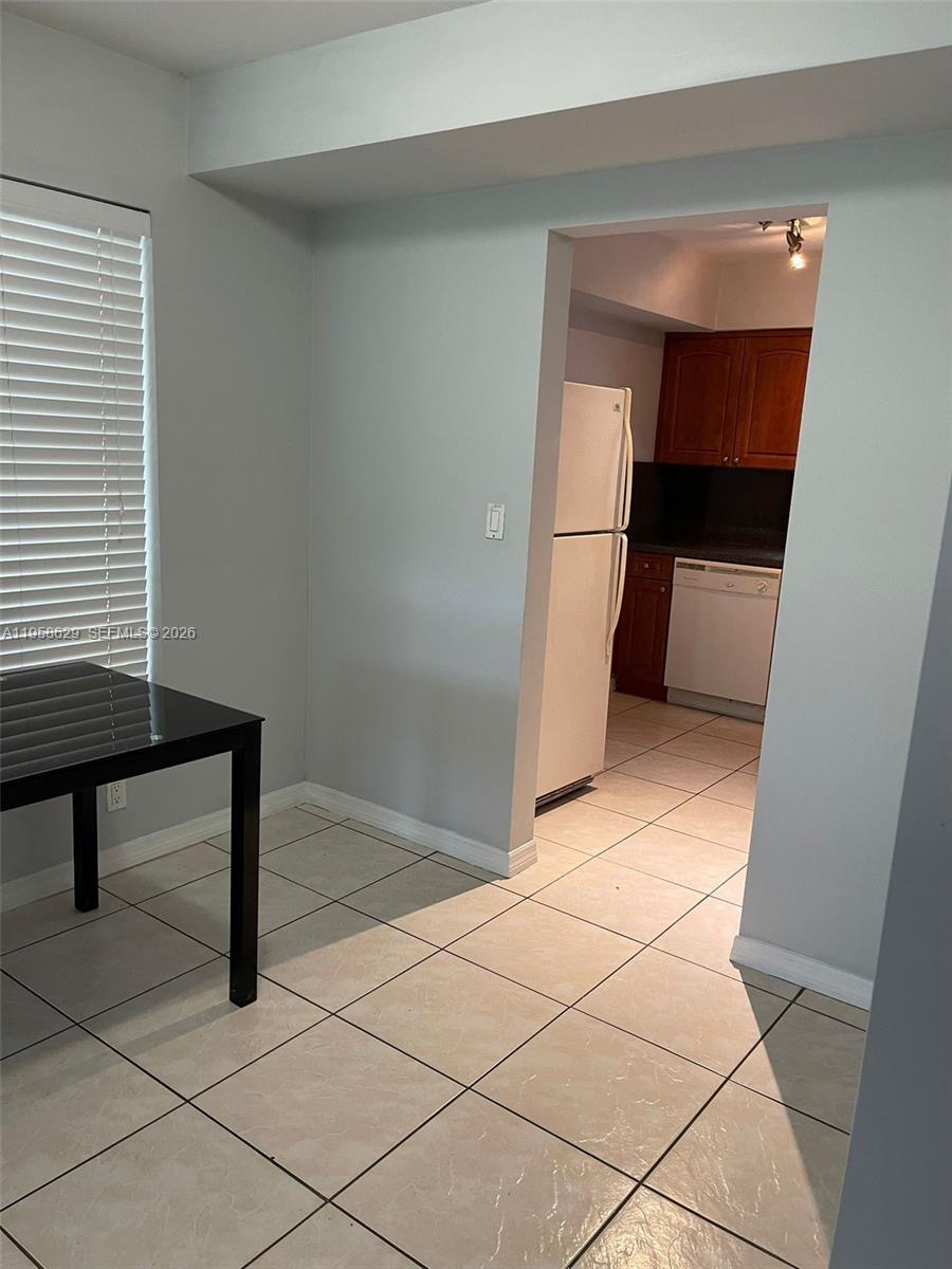 A dining area with tile flooring leads into a kitchen featuring wooden cabinets and appliances — 7670 SW 82nd St # H113, Miami FL 33143, MIAMI, FL