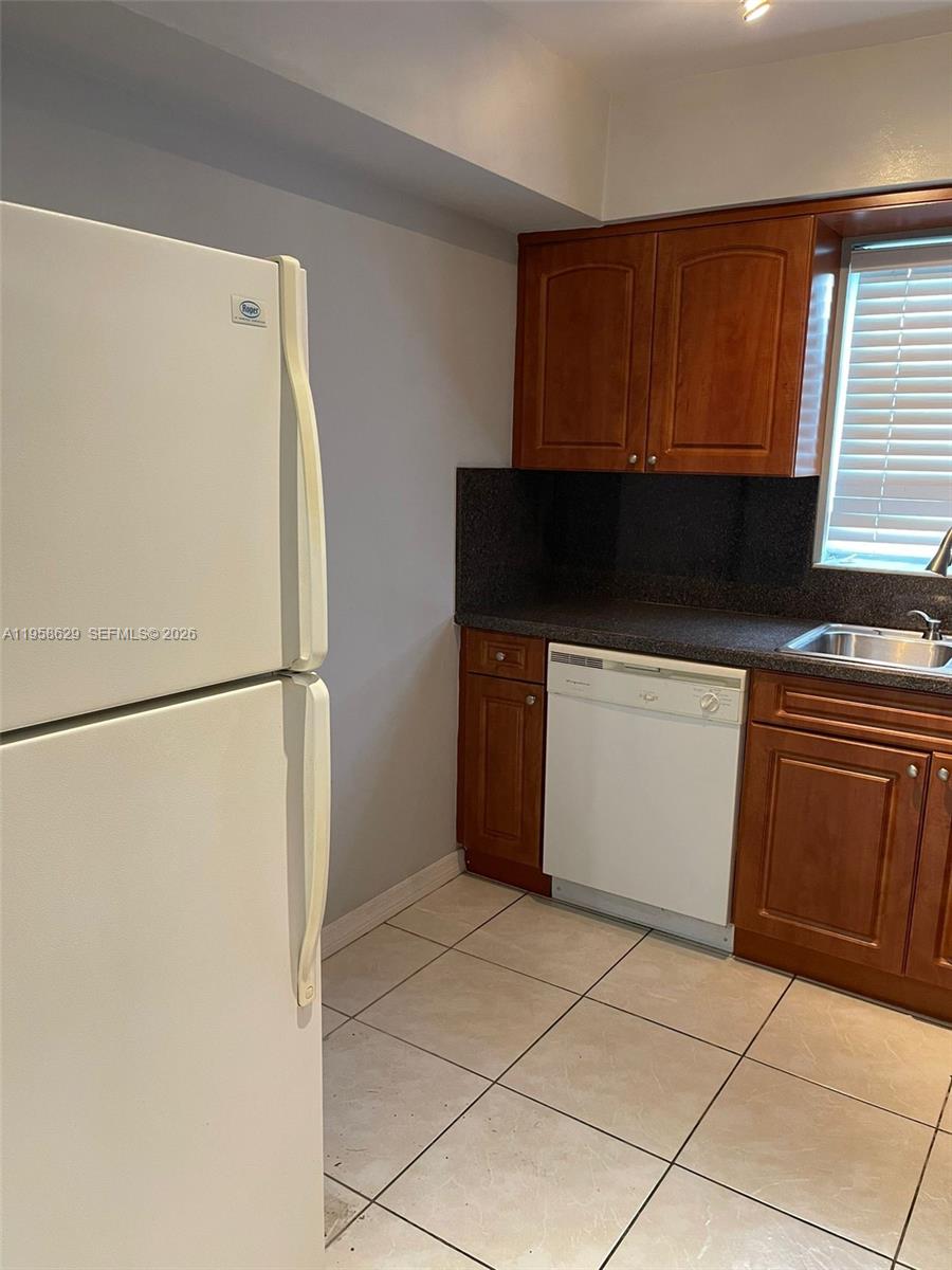 A kitchen features wood cabinets, a white dishwasher, a white refrigerator, and tiled flooring — 7670 SW 82nd St # H113, Miami FL 33143, MIAMI, FL