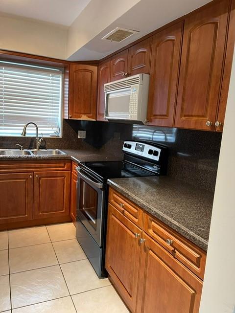 A kitchen with wood cabinets, dark countertops, a stainless steel stove, and a window — 7670 SW 82nd St # H113, Miami FL 33143, MIAMI, FL