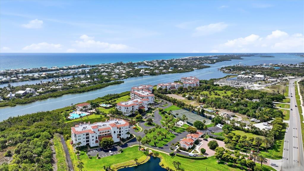 An aerial view shows a coastal apartment complex with a pool, tennis courts, and landscaping — 11160 HACIENDA DEL MAR BOULEVARD UNIT 202, PLACIDA, FL