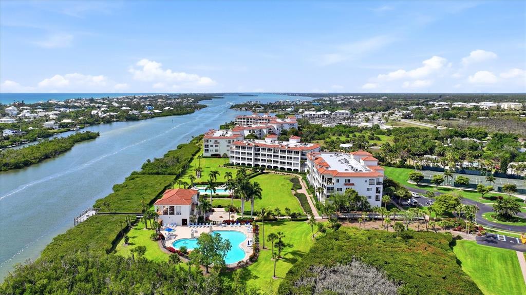 An aerial view shows a multi-story residential complex with a pool and waterfront access — 11160 HACIENDA DEL MAR BOULEVARD UNIT 202, PLACIDA, FL